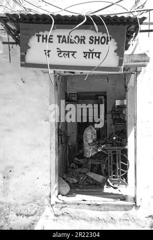 A tailor in a small shop with an old sewing machine working Stock Photo