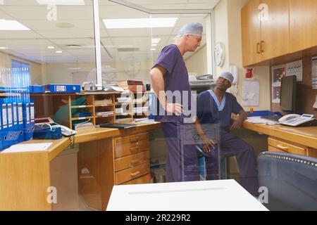 Discussing possible techniques for an upcoming surgery. two surgeons having a discussion in a hospital. Stock Photo