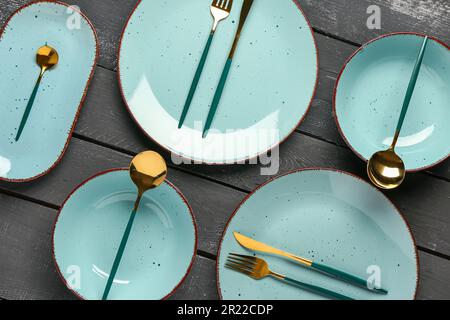Table setting with clean plates and cutlery on black wooden table Stock Photo
