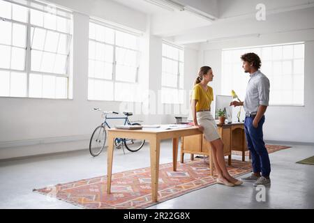 Having a quick informal business meeting. Full length shot of two young people talking in a studio. Stock Photo