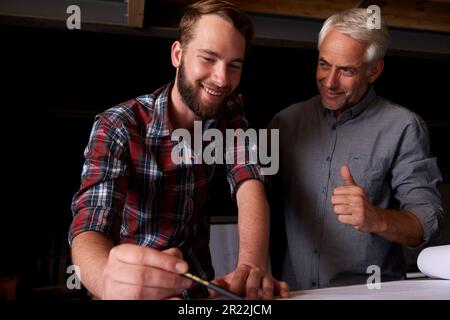 Your work is looking good. a senior architect showing approval of his junior coworkers drawings. Stock Photo