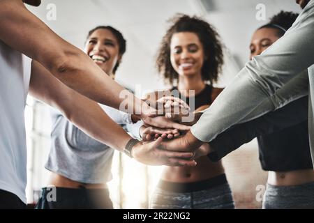 Fitness can be contagious. a group of young people joining their hands together in solidarity at a gym. Stock Photo