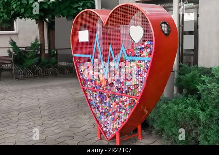 Heart shaped red recycling container for plastic caps outdoors Stock Photo