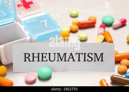 Card with word Rheumatism and pills on table, closeup Stock Photo