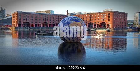 Luke Jerram Floating Earth comes to Liverpool's Royal Albert Dock, looking majestic on a sunset evening, in front of the Victorian port warehouses Stock Photo