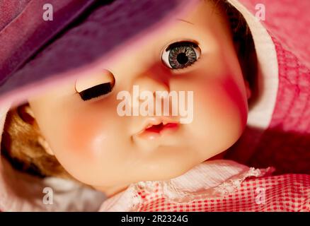 Close up of the face of a vintage doll with one eye closed and one