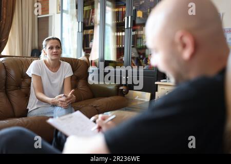Careful psychologist making notes in office listens to woman Stock Photo