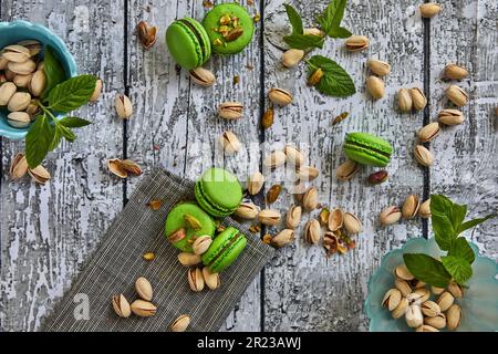 Green color pistachio macarons with pistachios on gray wooden background Stock Photo