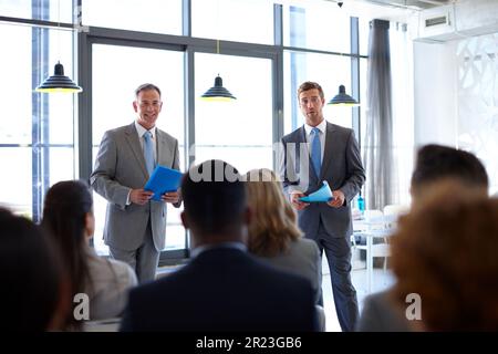 Are there any questions. two businessmen giving a presentation to their coworkers. Stock Photo