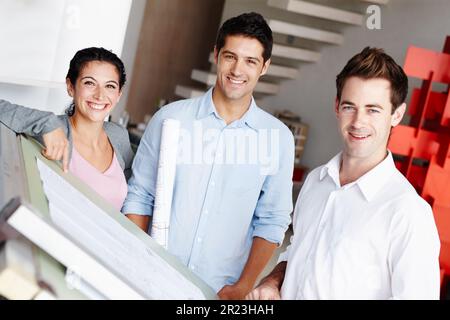 Team of successful architects. Portrait of three talented architects working on their design blueprints together. Stock Photo