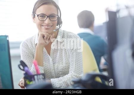 Friendly face of customer service. an attractive young customer service representative working at her desk in an office. Stock Photo