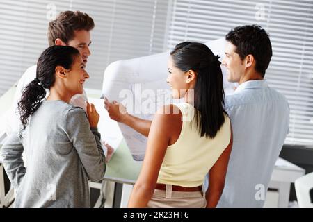 Going over the blueprints together. Four talented architects working on design blueprints together. Stock Photo