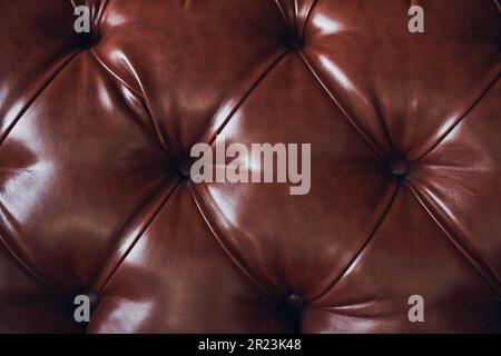 Faux brown leather close-up, upholstered furniture in retro Chesterfield style with deep diamond pattern and buttons. High quality photo Stock Photo