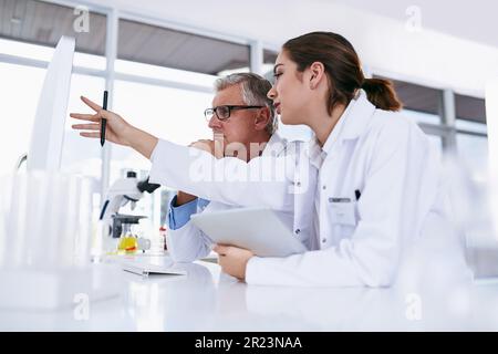 Scientist, tablet and teamwork in science experiment, results or collaboration on computer at the laboratory. Woman and man mentor in medical research Stock Photo
