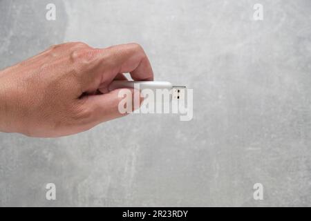 Man hand holds USB flash drive, on gray background Stock Photo