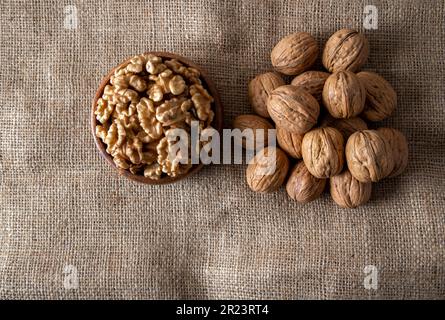 Peel walnuts and whole walnuts on burlap sack,top view Stock Photo