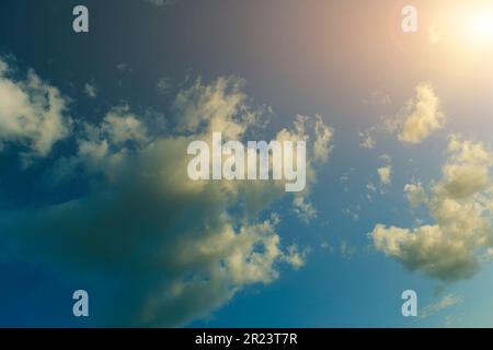 Clouds against blue sky against bright sun Stock Photo