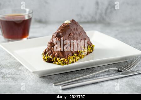 Dessert Cake from Malaga on stone table. Cake with banana inside, covered with chocolate sauce and hazelnuts Stock Photo