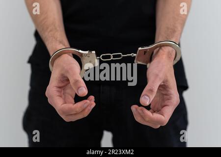 arrested man with cuffed hands behind prison bars. Stock Photo