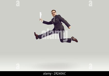 Overjoyed young Caucasian business man in pose of running person smiles at moment of jump Stock Photo