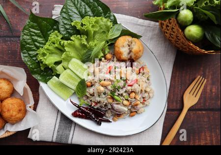 Yam Naem Khao Tod:  Thai fermented Spicy pork Salad with Crispy Rice ball at top view with vegetables on the side - Flat lay Thai appetizer food Stock Photo