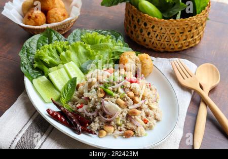 Yam Naem Khao Tod:  Thai fermented Spicy pork Salad with Crispy Rice ball at top view with vegetables on the side - Flat lay Thai appetizer food Stock Photo