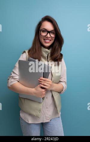 positive 30s lady student holding documents and laptop on empty space background Stock Photo