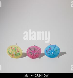 Three sunshades of various colors with sharp shadows with copy space. Minimal Summer scene. Stock Photo