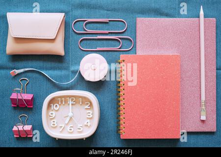 Pink stationery office supply on blue fabric desk background. flat lay, top view Stock Photo