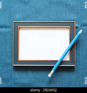 Navy picture frame with white blank paper and pencil on blue fabric background. top view, copy space Stock Photo