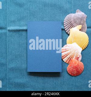 Blank memo paper with summer marine seashell on blue fabric background. top view, copy space Stock Photo