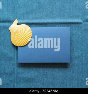 Blank memo paper with summer marine seashell on blue fabric background. top view, copy space Stock Photo