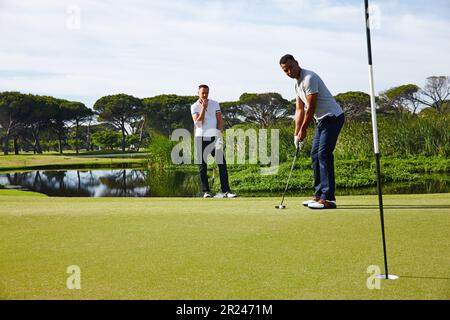 Perfecting his putt. two handsome men on the putting green. Stock Photo