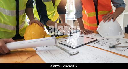 construction engineers team using blueprint and tablet of project plan brainstorming and working together at construction building, Architecture and Stock Photo