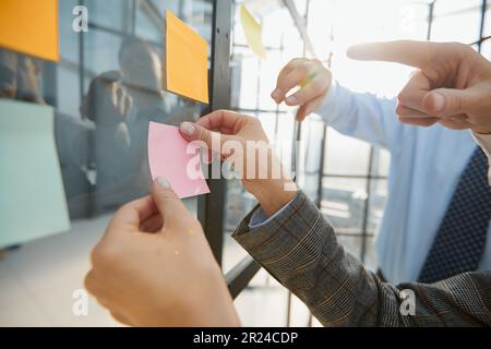 hand glues empty sticker on office window. Stock Photo