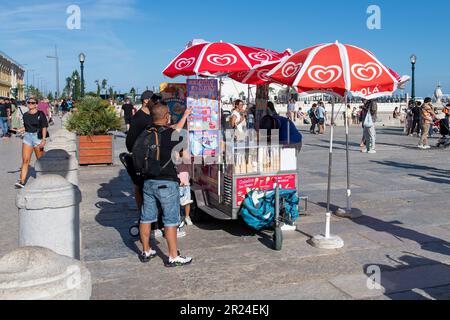 Lisbon, Portugal-October 2022: Close up of an ice cream cart, vendor and customers along the waterfront of Tagus river on historic Praça do Comércio Stock Photo