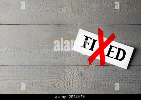 Card with optimistic word Fixed on grey wooden background, space for text. Letter X made of red adhesive tape Stock Photo