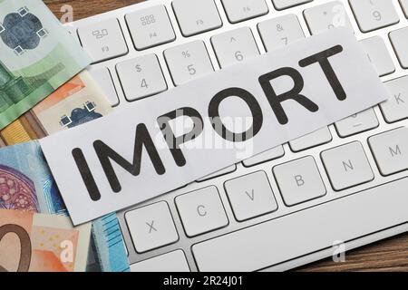 Card with word Import, computer keyboard and money on wooden table, top view Stock Photo