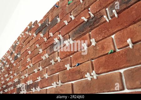 Decorative bricks with tile leveling system on white wall Stock Photo