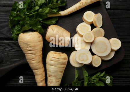 Whole and cut parsnips on black wooden table, flat lay Stock Photo