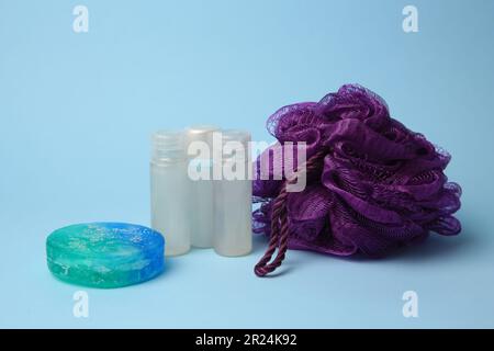 Purple shower puff and cosmetic products on light blue background Stock Photo