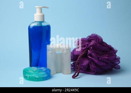 Purple shower puff and cosmetic products on light blue background Stock Photo