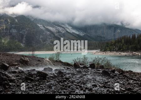 A picturesque scene of a mountain landscape with a steaming hot spring nestled nearby Stock Photo