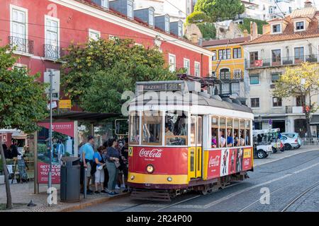 Lisbon, Portugal-October 2022: Close up view of a red colored tramcar at a stop with passengers waiting to board  in the Alfama neighborhood Stock Photo