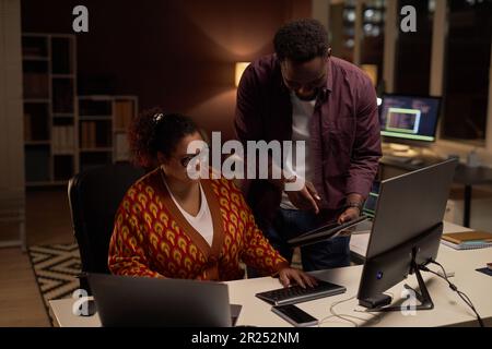 Colleagues working over computer program in team, they discussing presentation on digital tablet during their deadline in office Stock Photo
