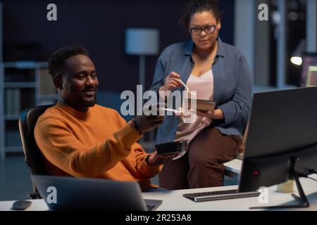 Programmers having lunch and working over computer program till late night in IT office Stock Photo