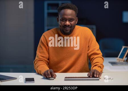 Portrait of African American programmer smiling at camera while using laptop at his work in IT office Stock Photo