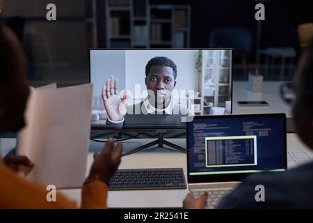 Programmers discussing computer program with colleague online during digital meeting in office Stock Photo