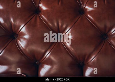 Faux brown leather close-up, upholstered furniture in retro Chesterfield style with deep diamond pattern and buttons. High quality photo Stock Photo