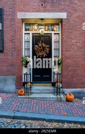 Boston, Massachusetts - November 29, 2018: Acorn Street Beacon Hill house during fall harvest with American Flag and cobblestone alley in Boston Stock Photo